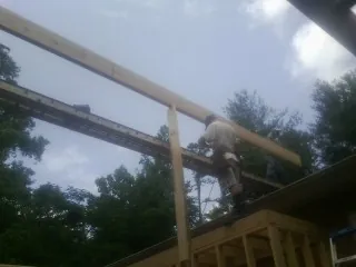 Carpenter setting a ridge beam over a new addition frame in La Salle
