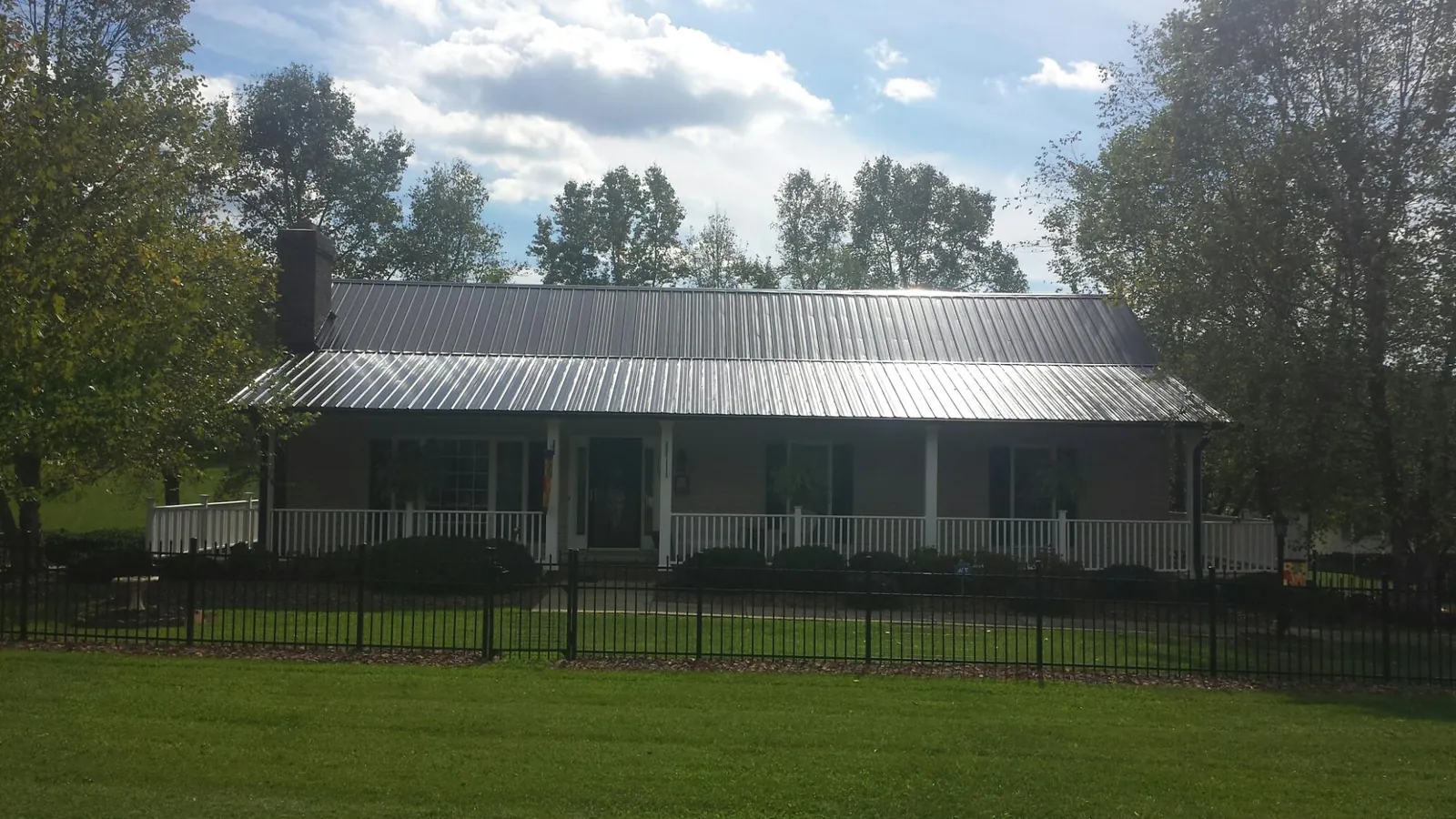 Gray metal roof on a brick ranch with a full width front porch — Gutter Guard Installation work by our crew in La Salle